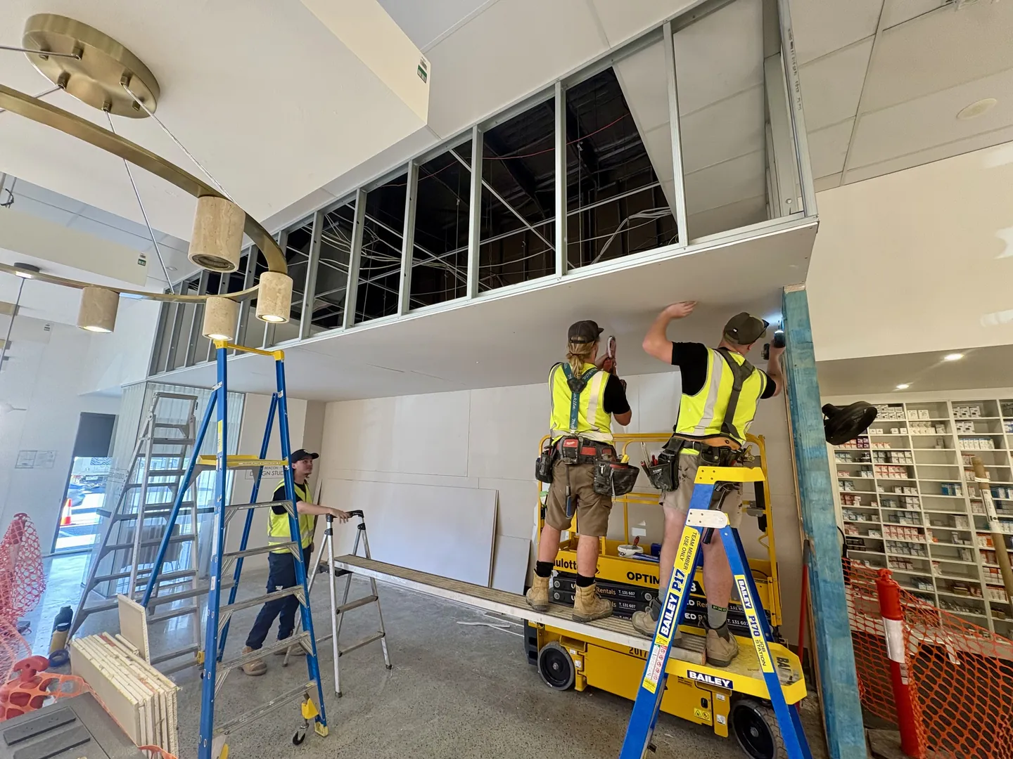 Combo Constructions crew installing a shopfitting bulkhead from scissor lifts