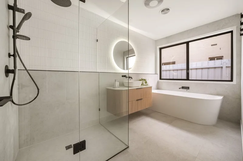 Bathroom with a walk in shower, freestanding bath and round backlit mirror