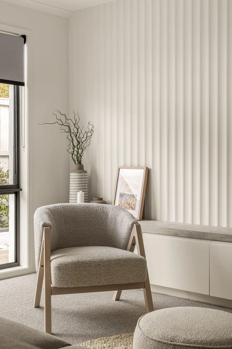 Living area with an upholstered armchair beside sheer curtains
