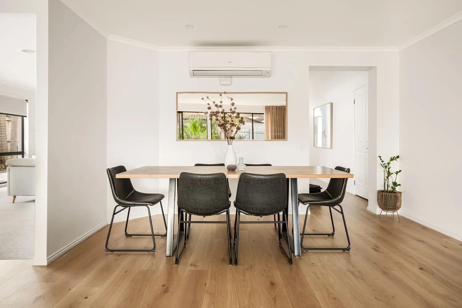 Dining room with timber flooring and black dining chairs at the Patterson Lakes renovation